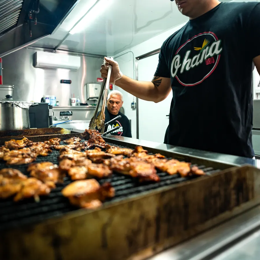 Ohana BBQ crew grilling teriyaki chicken in the trailer